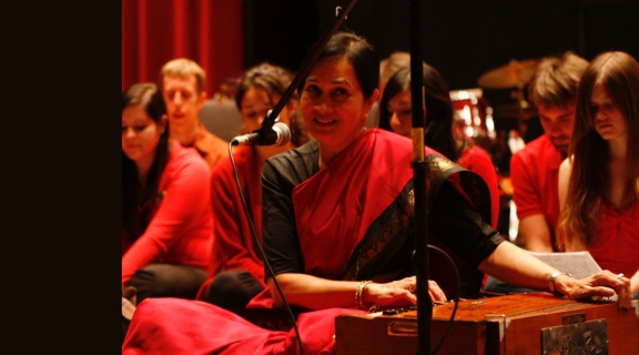 Rita Sahai in red by an instrument
